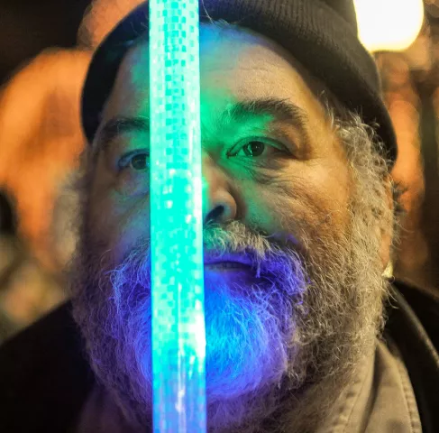 Ray Murphy of St Paul is lit by a glow stick as he watches the Winter Carnival Torchlight Parade, on Fifth Street in downtown St. Paul on Saturday, Feb. 6, 2016. (Special to the Pioneer Press: Craig Lassig)
