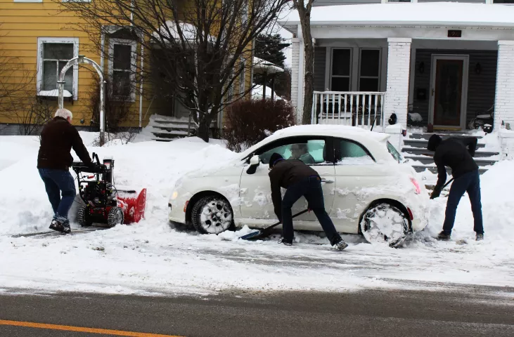 Gary Seal uses a snow blower to help clear a path for a car trapped in Racine, Wis., Monday, Jan. 28, 2019, while Kaleb Miller, 17, and Ben Jarvis, 18, use their shovels to break up ice underneath the car's tires. Snowplow drivers had trouble keeping up with the snow in Minnesota and Wisconsin, where some areas got as much as 15 inches (38 centimeters). Chicago-area commuters woke up to heavy snowfall, with more than 5 inches (12.7 centimeters) already on the ground. In Michigan, non-essential government of