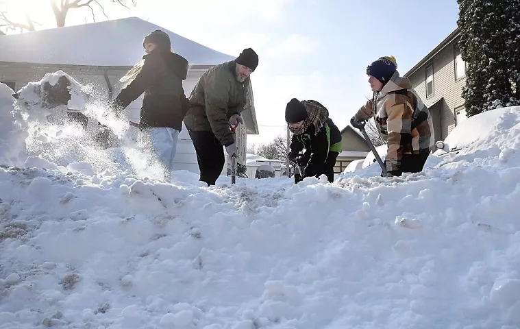 Nate LeBoutillier and his children, from left to right, Valerie, Gordie and Archie work to clear their neighbor's driveway Monday, Jan. 28, 2019, in North Mankato, Minn. (Pat Christman/The Free Press via AP)
