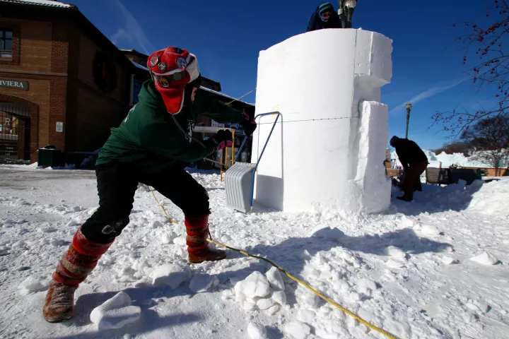 Minnesota snow sculptors Heather Friedli, left, and Adam Turner try to saw off a piece of snow off their block at the U.S. National Snow Sculpting Championship in Lake Geneva, Wis., Thursday, Jan. 31, 2019. Each team gets a cylinder of snow 8 feet across and 9 feet high, to carve with saws, axes, files, scaffolding, shovels and other homemade implements. The entries will be judged Saturday on creativity, technique and message. Competitors choose the winner. (AP Photo/Carrie Antlfinger)